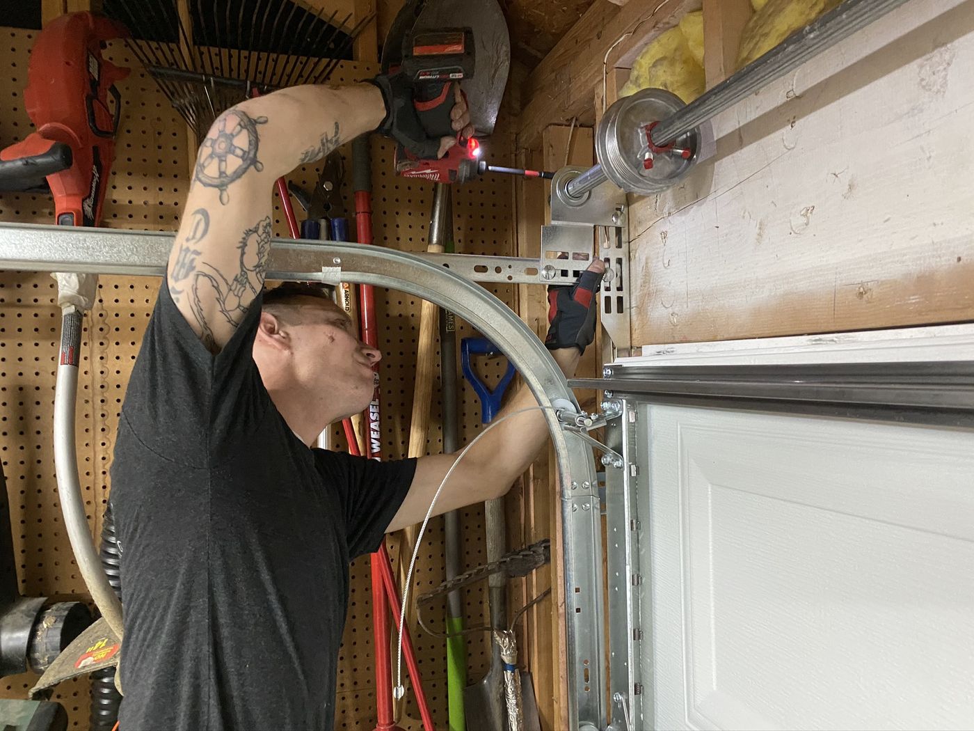 WarriorNOW veteran using a drill on a garage door track and cable drum